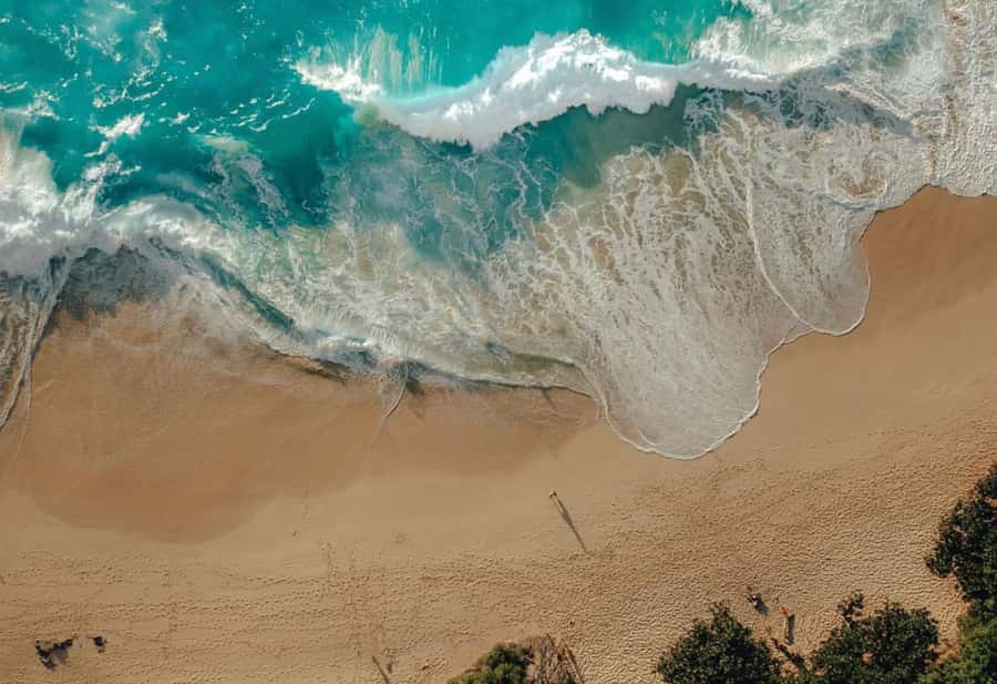 A wave breaking gold on dark sand at the end of the Seminyak strip